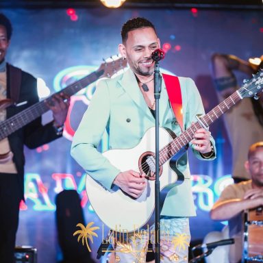 Sandro Reyes con guitarra acompañado de músicos en un show en directo.