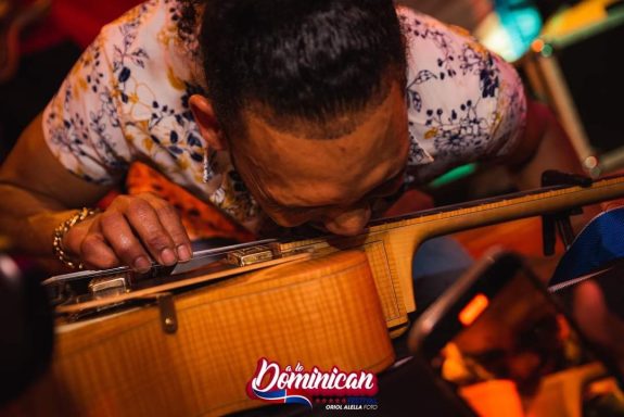 Sandro Reyes tocando un instrumento musical en un ambiente festivo y colorido.